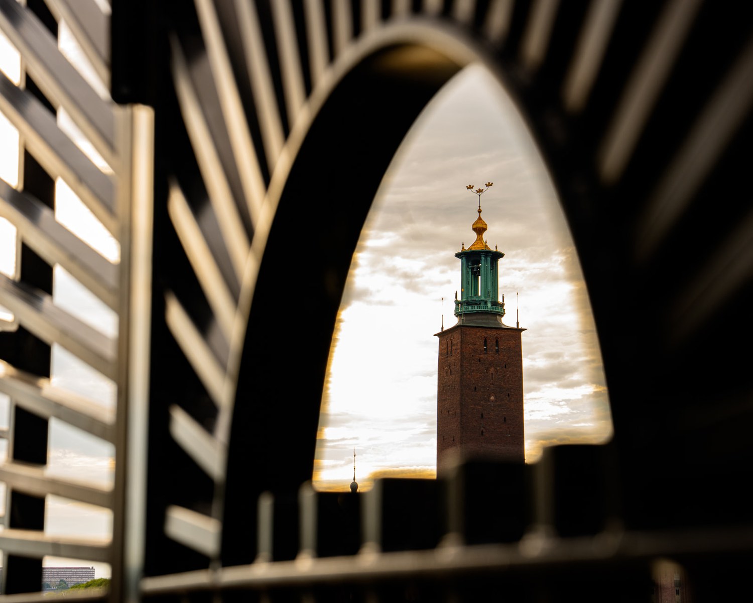 Stockholms stadshustorn med tre kronor, fotograferat genom ett räcke i kvällsljus